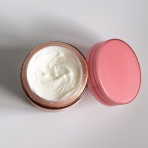 An open jar of white cream with a pink lid beside it.